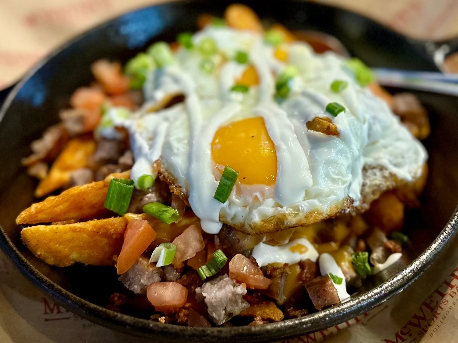 Restaurant food photography of loaded breakfast skillet with eggs, potatoes, meat and vegetables