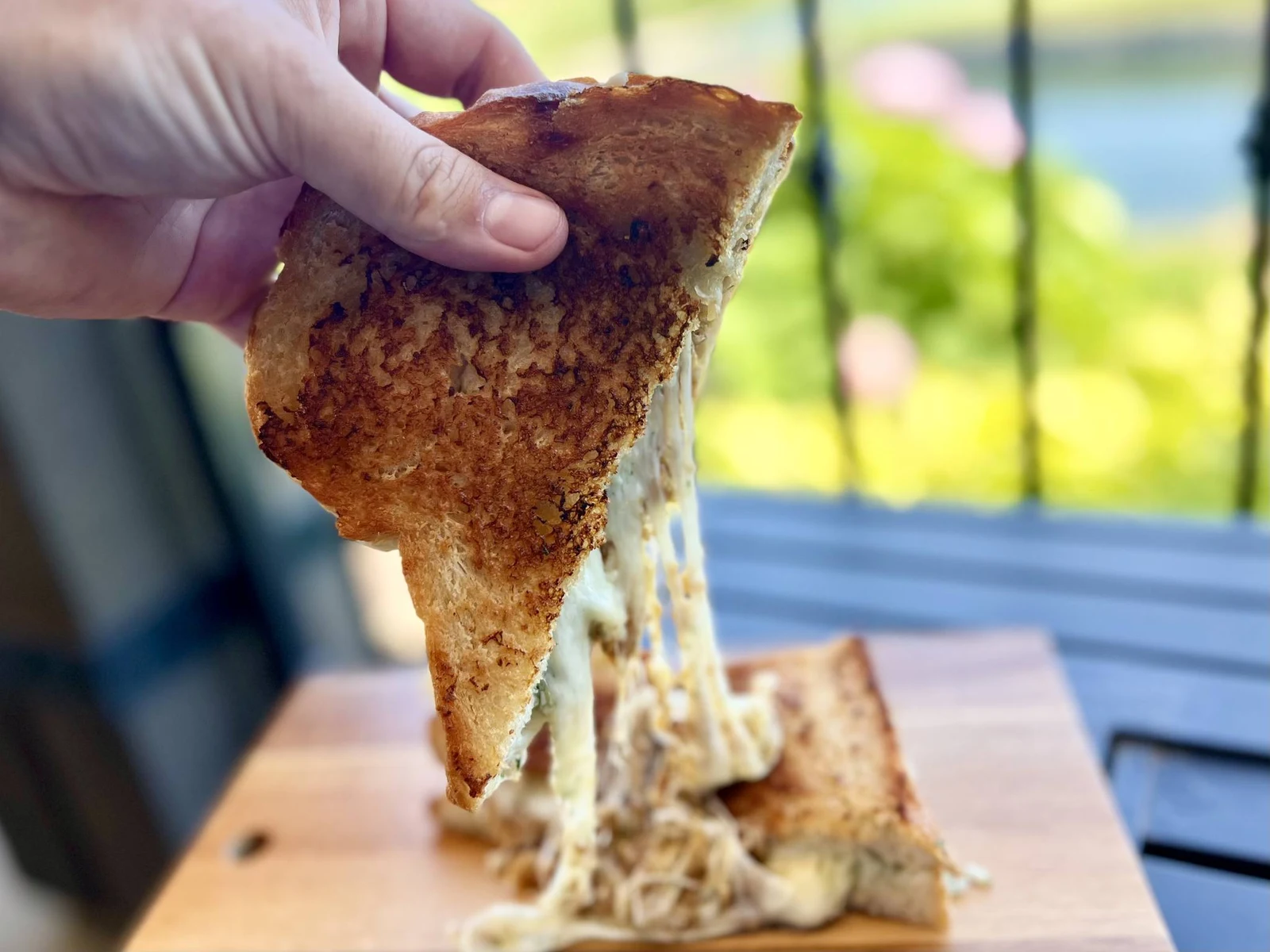Restaurant food photography close-up cheese pull from toasted sandwich outdoors