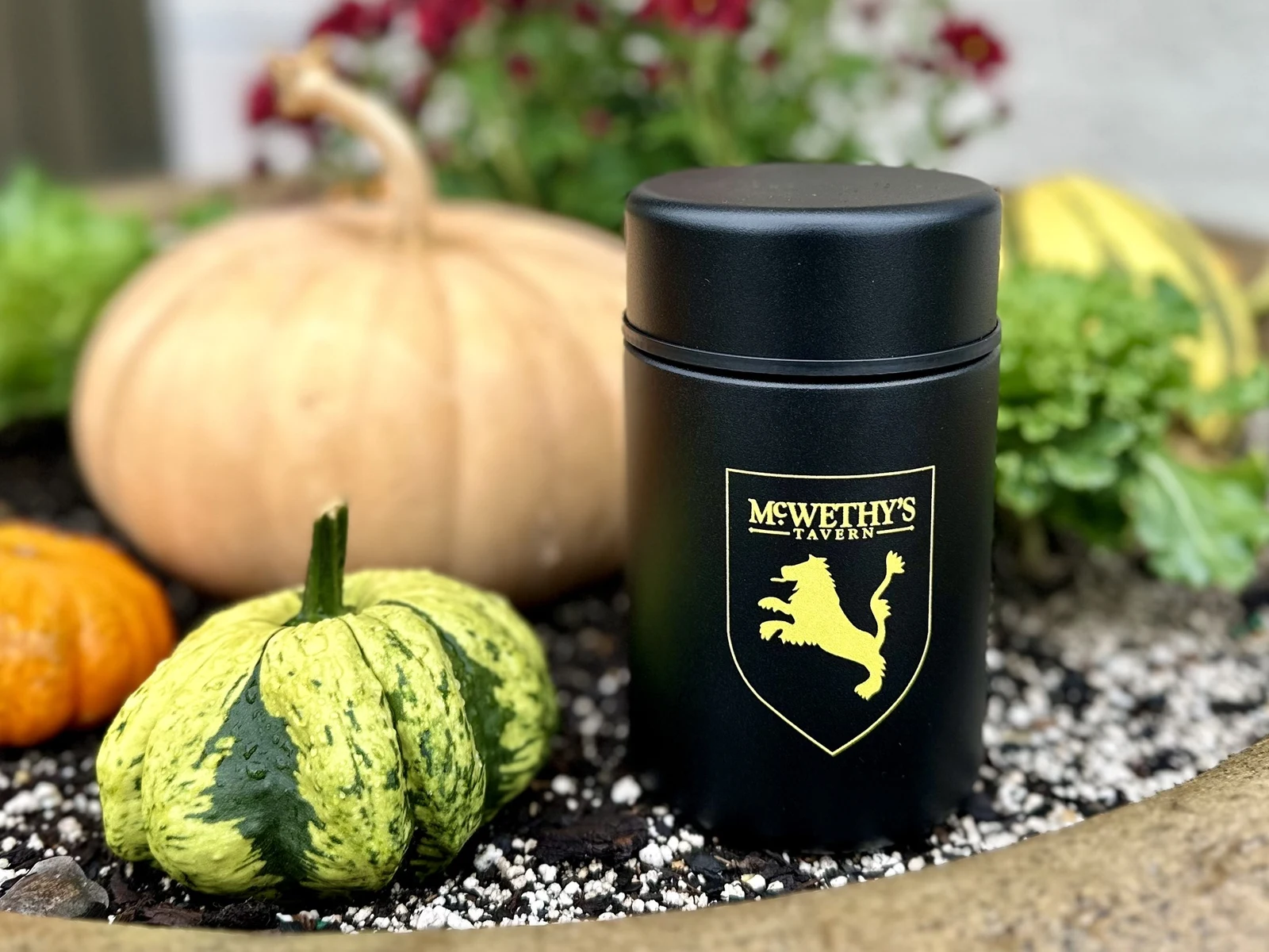 Product photography of McWethy's branded insulated tumbler among fall pumpkins