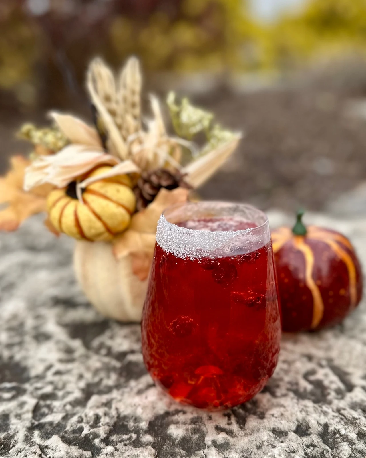 Cocktail photography of red seasonal cocktail among pumpkins