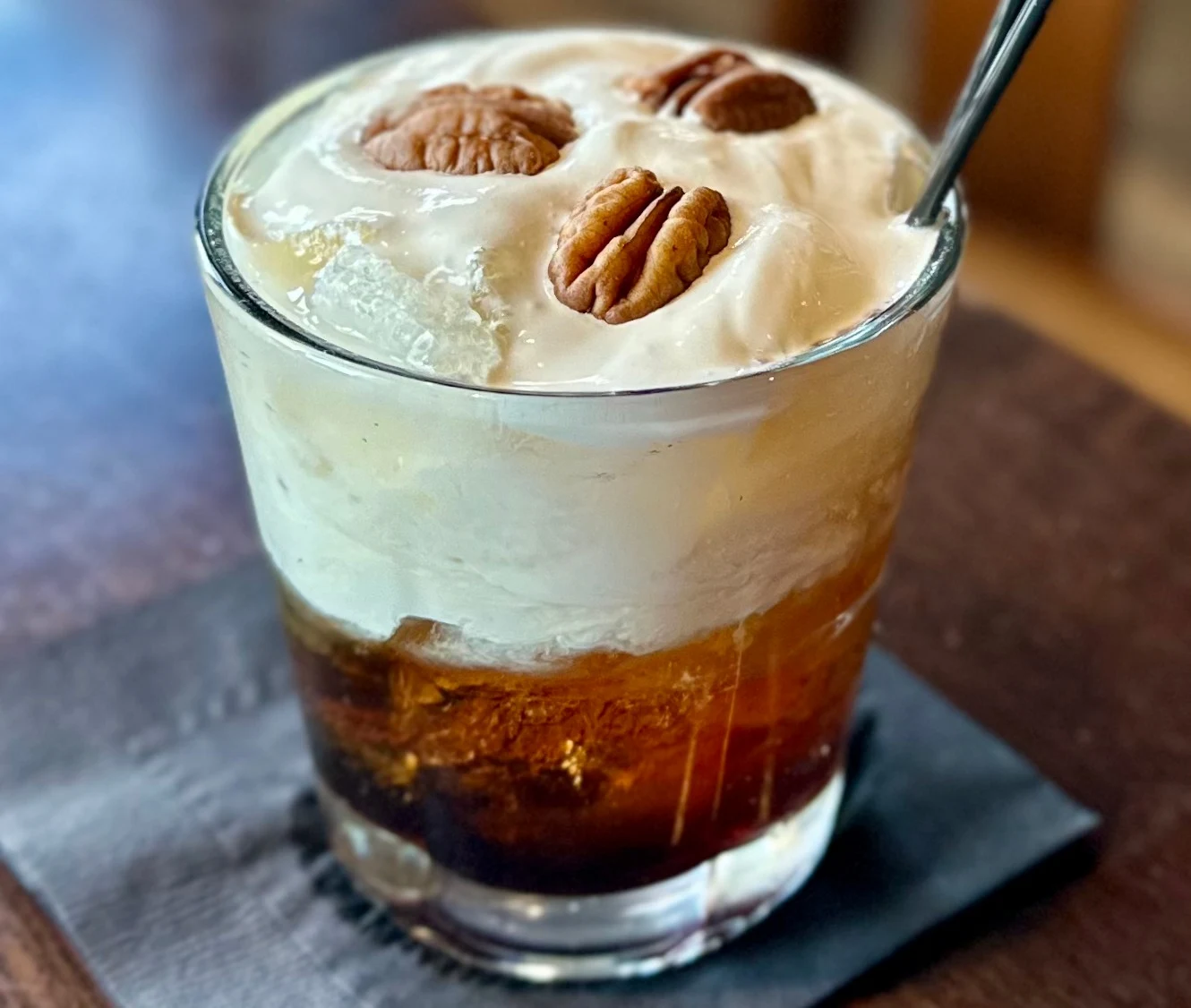 Cocktail photography of layered cocktail with cream and pecan garnish