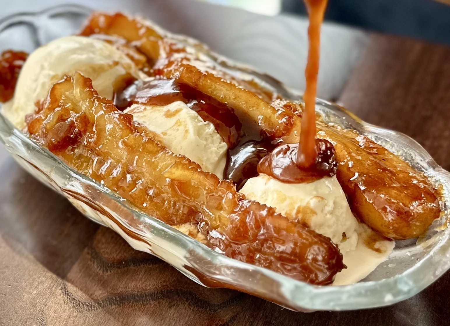 Commercial food photography of caramelized fruit dessert and vanilla ice cream with sauce being poured