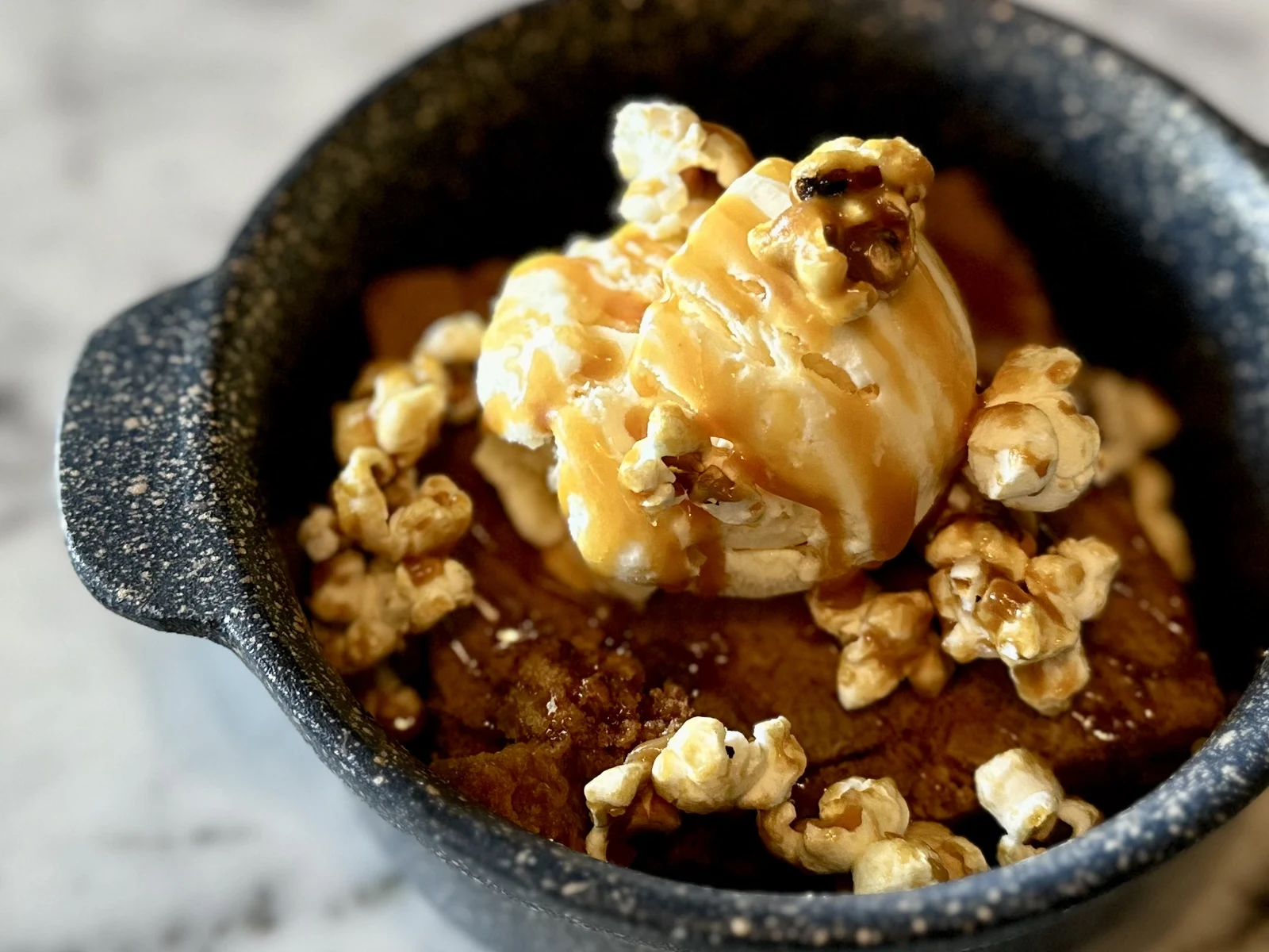Restaurant dessert photography of warm skillet dessert with vanilla ice cream, caramel sauce and popcorn