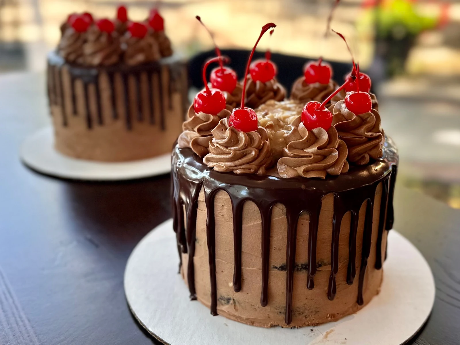 Commercial dessert photography of chocolate cakes topped with chocolate ganache, whipped frosting and cherries