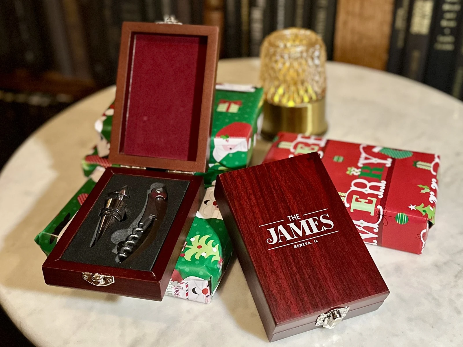 Product photography of The James Geneva branded wooden wine-tool gift set displayed with wrapped gifts